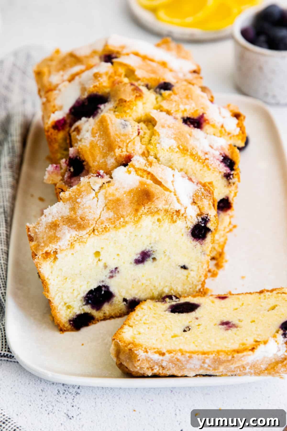 Exquisitely sliced lemon blueberry pound cake presented on a pristine white platter, showcasing its tender crumb and scattered blueberries.