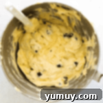 blueberry pound cake batter in a stand mixer bowl with a rubber spatula.