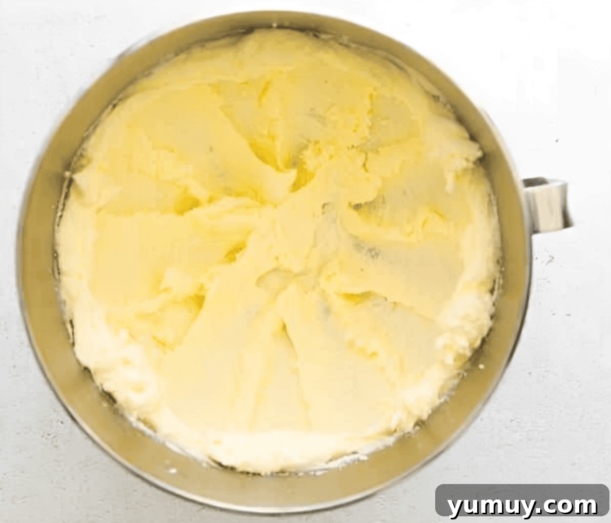 Creamed butter and sugar mixture in a stand mixer bowl, showing a light and fluffy texture.
