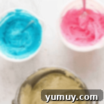 pink, blue, and white buttercream in bowls.