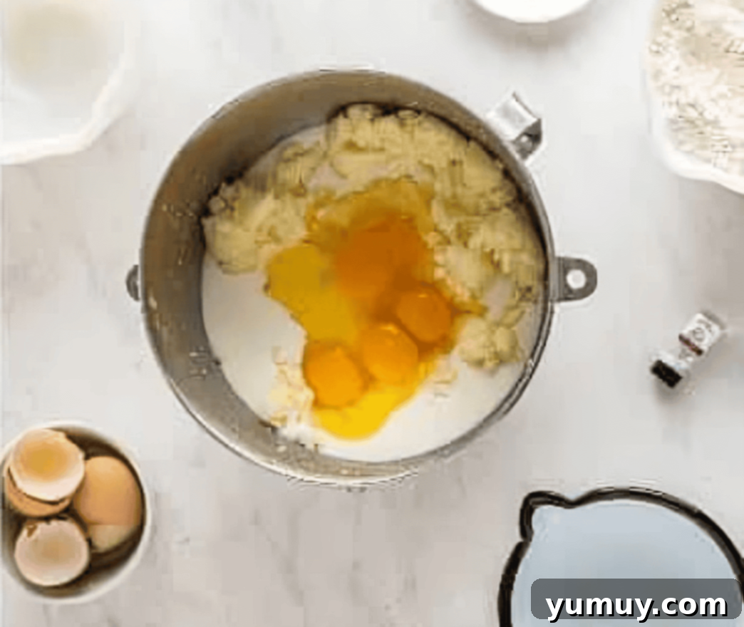 eggs and milk added to cake batter in a stainless bowl.
