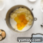 eggs and milk added to cake batter in a stainless bowl.