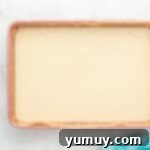 Rainbow poke cake batter evenly spread in a rectangular baking pan, ready for baking.