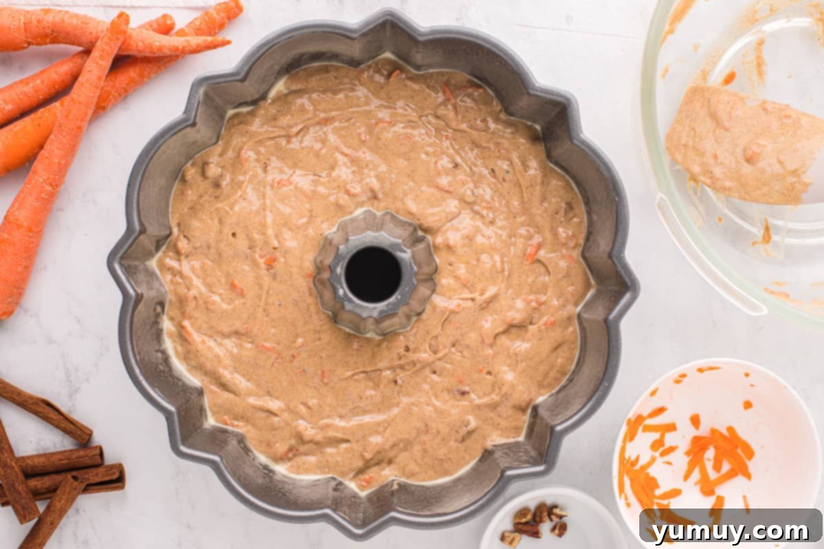 The smooth, orange-flecked carrot bundt cake batter expertly poured into a bundt pan, ready for baking.