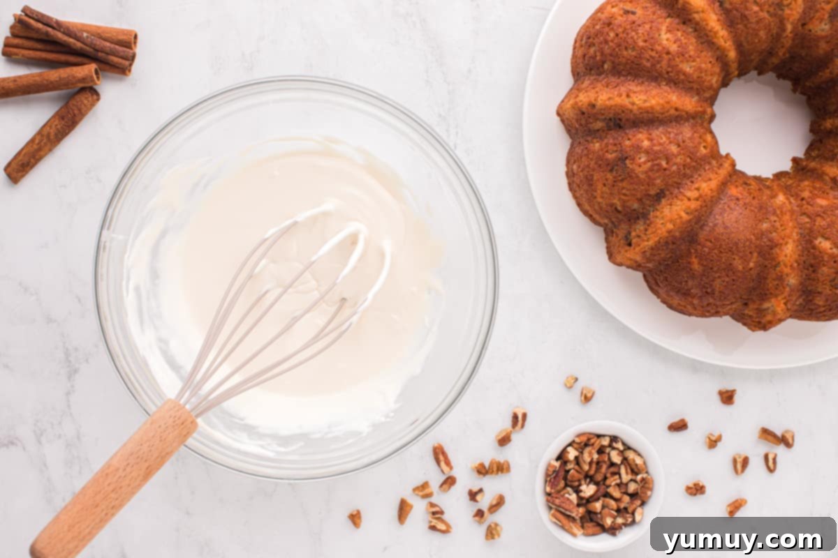 A close-up of the luscious cream cheese frosting, perfectly whisked in a clear glass bowl, ready to become the final touch for the carrot bundt cake.
