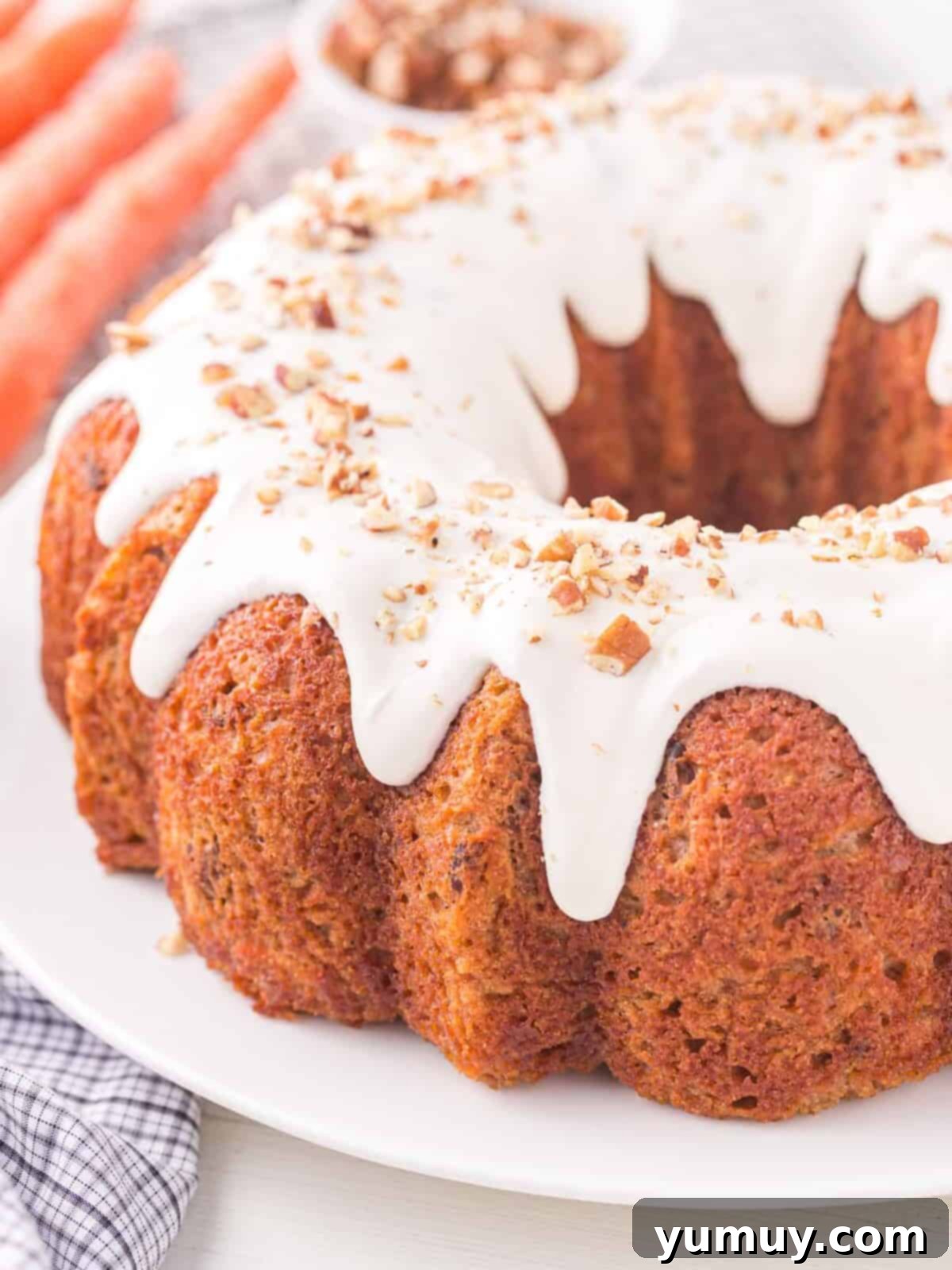 A magnificent full view of a cream-cheese-glazed carrot bundt cake presented on an elegant white cake plate.