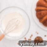 Smooth and creamy cream cheese frosting for carrot bundt cake, perfectly whisked in a glass bowl.