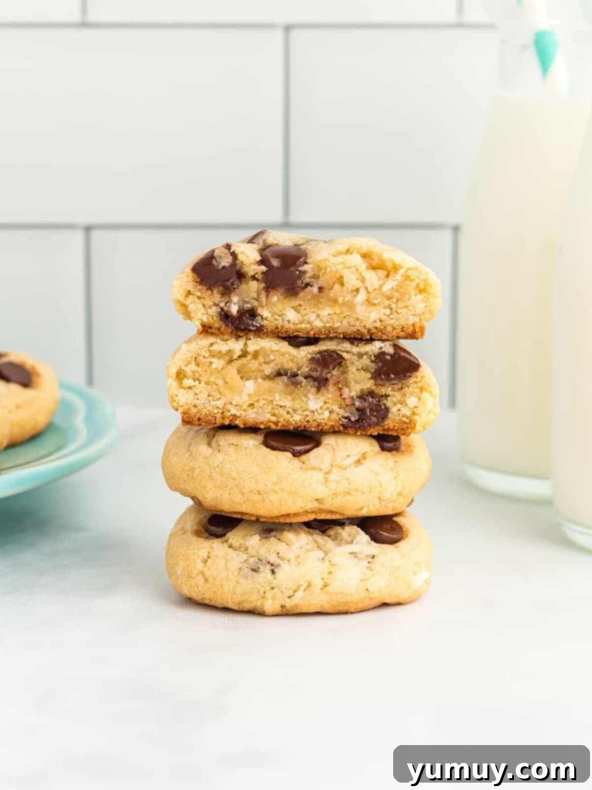 Tropical Coconut Chocolate Chip Delight 3 a halved shredded coconut and chocolate chip cookie stacked on top of 2 whole cookies to show the interior texture and golden brown edges.
