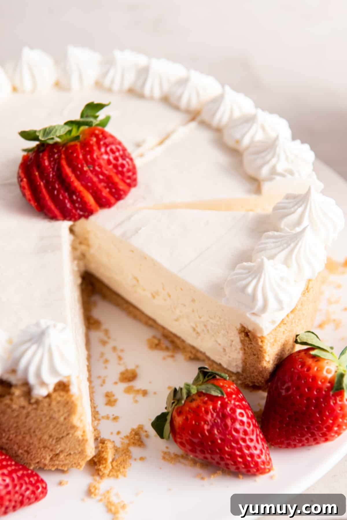 A pristine no-bake cheesecake, with a single slice carefully removed, showcasing its smooth, creamy interior and firm graham cracker crust.