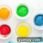 Five separate colored bowls of Jello cookie dough, mixed and ready for shaping.