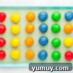 24 Jello cookie dough balls, neatly arranged on a blue baking sheet, ready for chilling.