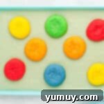 Eight perfectly baked Jello cookies, still warm on a blue baking sheet.