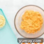 overhead view of orange creamsicle cookie dough in a glass bowl next to a bowl of white chocolate chips.