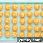 overhead view of 35 orange creamsicle cookie dough balls on a blue baking sheet.