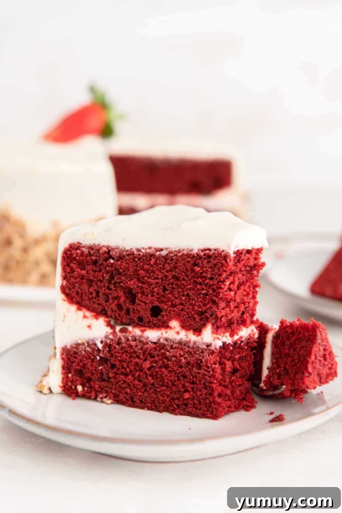 Effortless Red Velvet Cake from a Mix 2 side view of a partially eaten slice of red velvet cake on a white plate.