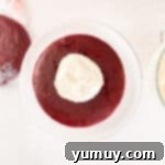 Effortless Red Velvet Cake from a Mix 12 a dollop of cream cheese frosting on a round of red velvet cake on a white cake stand.