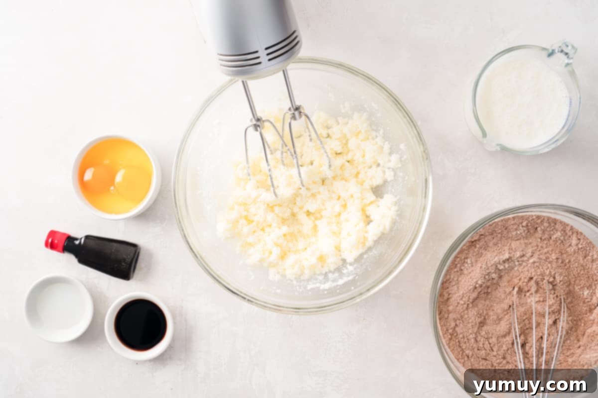 Effortless Red Velvet Cake from a Mix 16 butter being beaten in a glass bowl with a hand mixer.