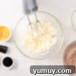 Effortless Red Velvet Cake from a Mix 6 butter being beaten in a glass bowl with a hand mixer.