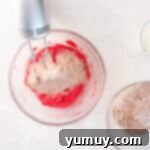 Effortless Red Velvet Cake from a Mix 8 dry ingredients for red velvet cake mixed into wet ingredients in a glass bowl with a hand mixer.