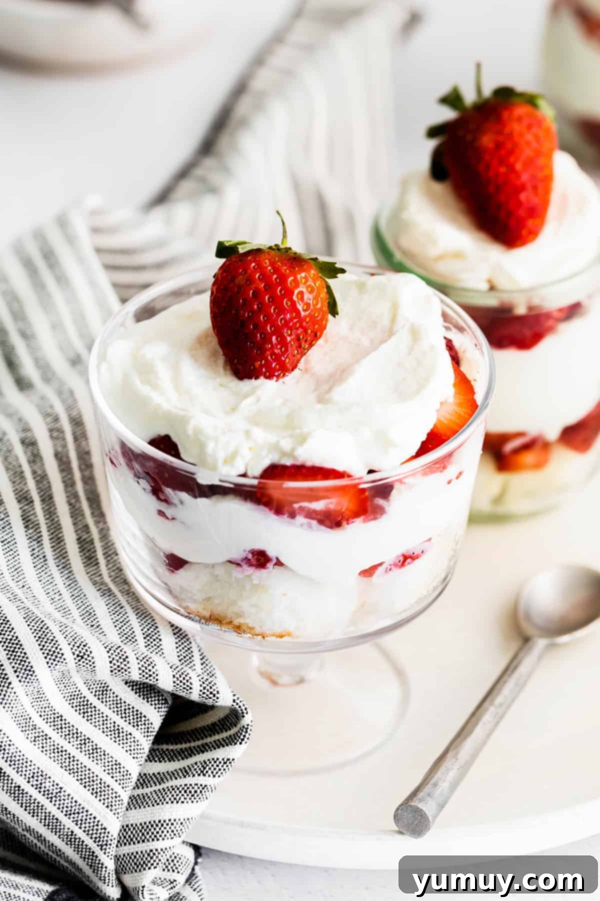 Two individual strawberry shortcake trifles served in charming small glass cups, highlighting the fresh strawberries and fluffy whipped cream.