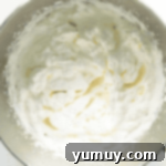 Fluffy, peaks-forming homemade whipped cream in a metal mixing bowl, ready to be chilled.