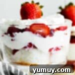 A beautifully layered strawberry shortcake trifle in a large glass bowl, with distinct layers of cake, strawberries, and whipped cream, ready to serve.