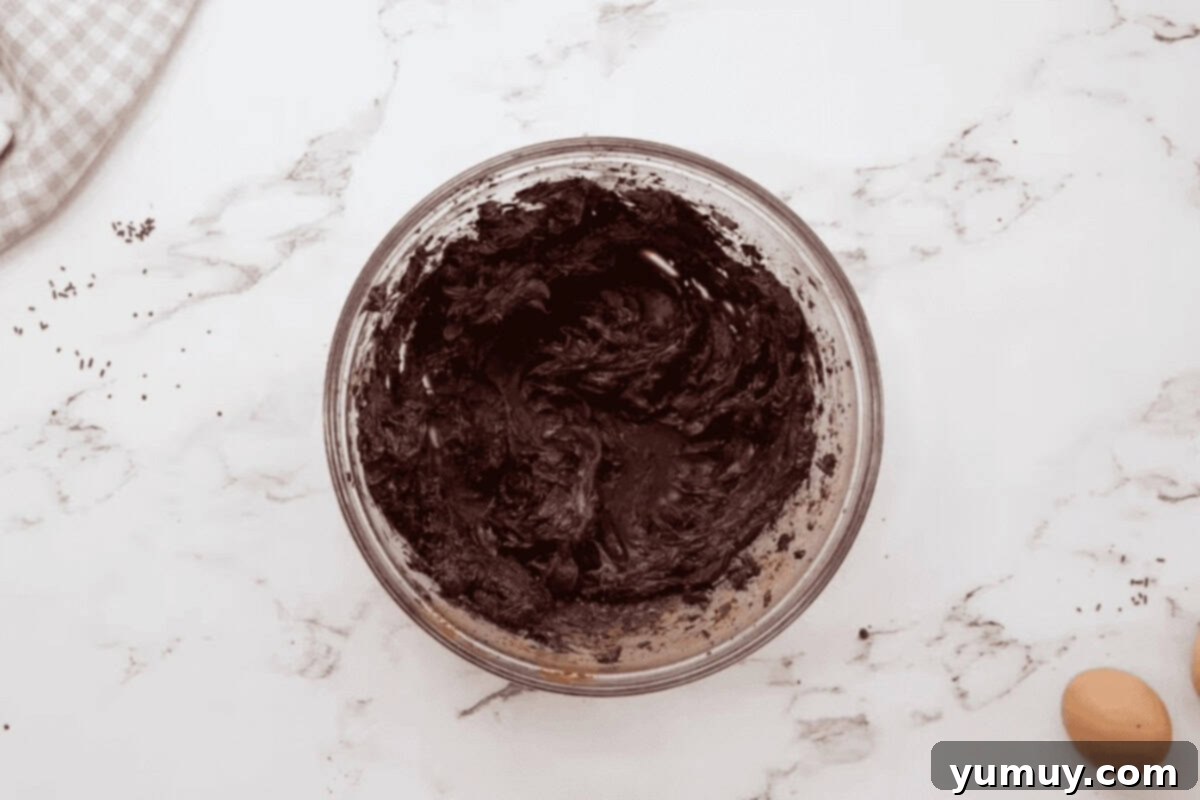 Close-up of creamed butter and cocoa mixture in a glass bowl, showing its rich, smooth texture.