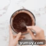 Whisking cocoa powder and boiling water in a glass bowl to bloom.