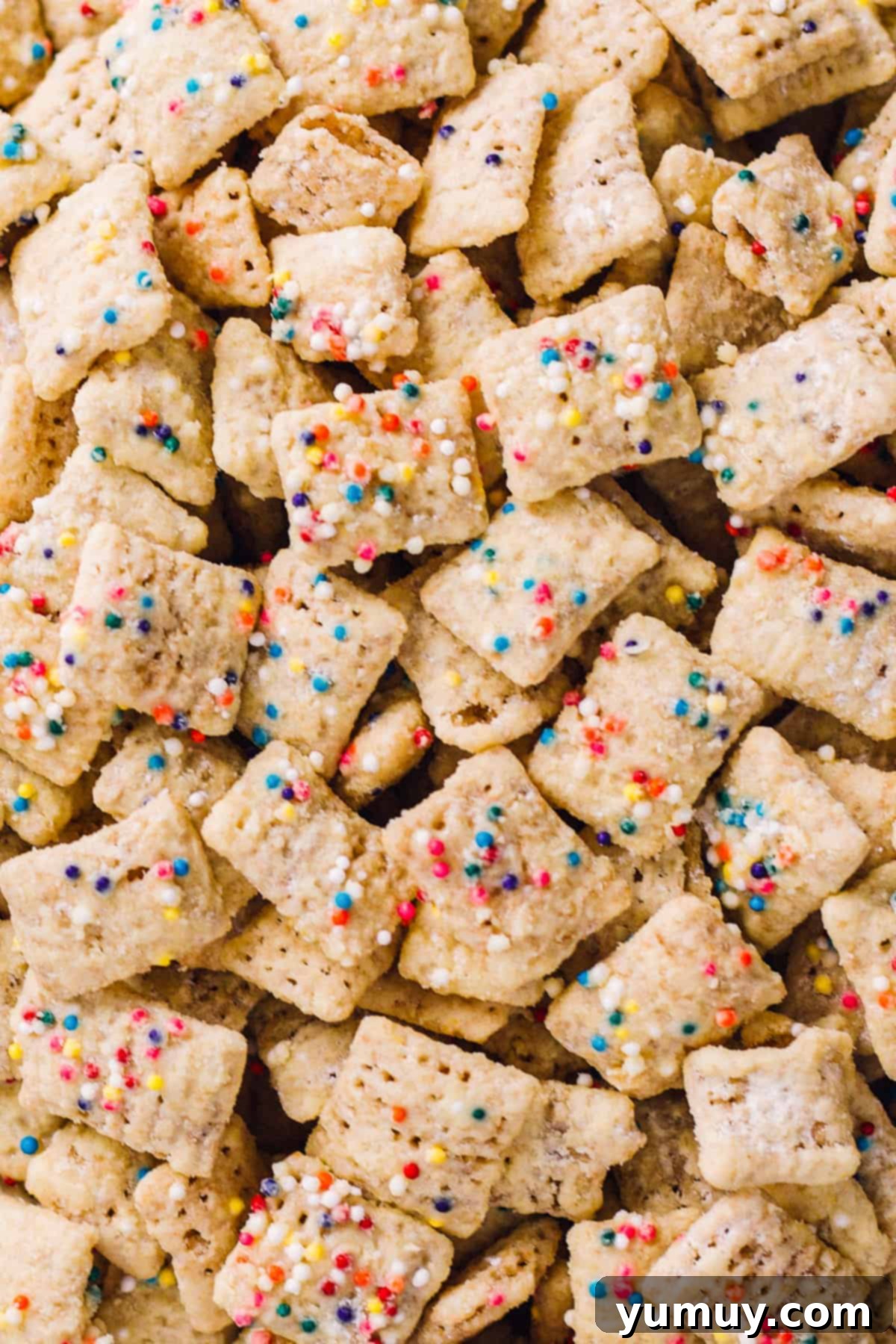 A close-up photograph showcasing the intricate details of cake batter puppy chow, highlighting its glossy coating and colorful sprinkles.