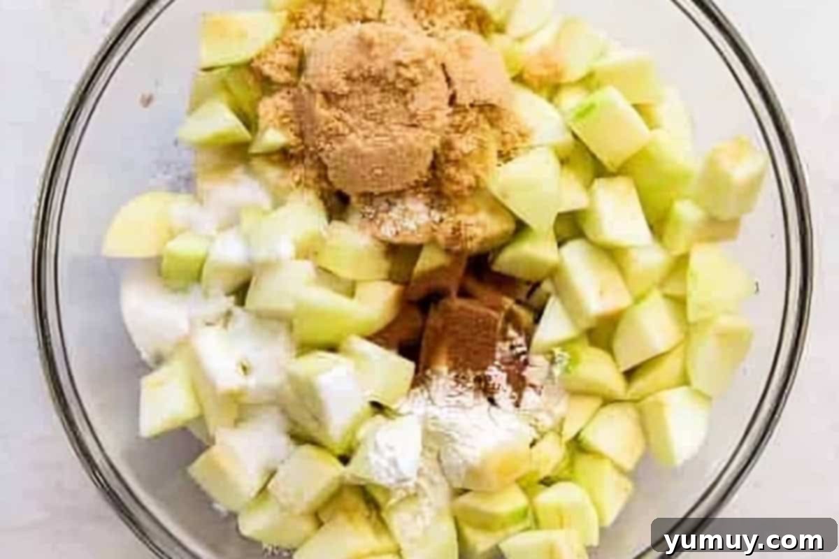 Homestyle Dutch Apple Pie 12 Chopped Granny Smith apples mixed with brown sugar, granulated sugar, flour, cinnamon, salt, and lemon juice in a large glass bowl.