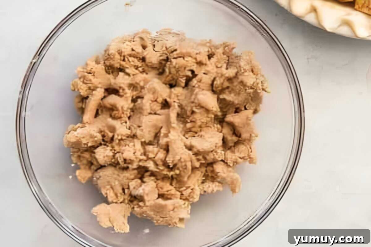 Homestyle Dutch Apple Pie 13 Streusel topping mixture in a glass bowl, with distinct coarse crumbs formed from flour, sugars, cinnamon, and butter.