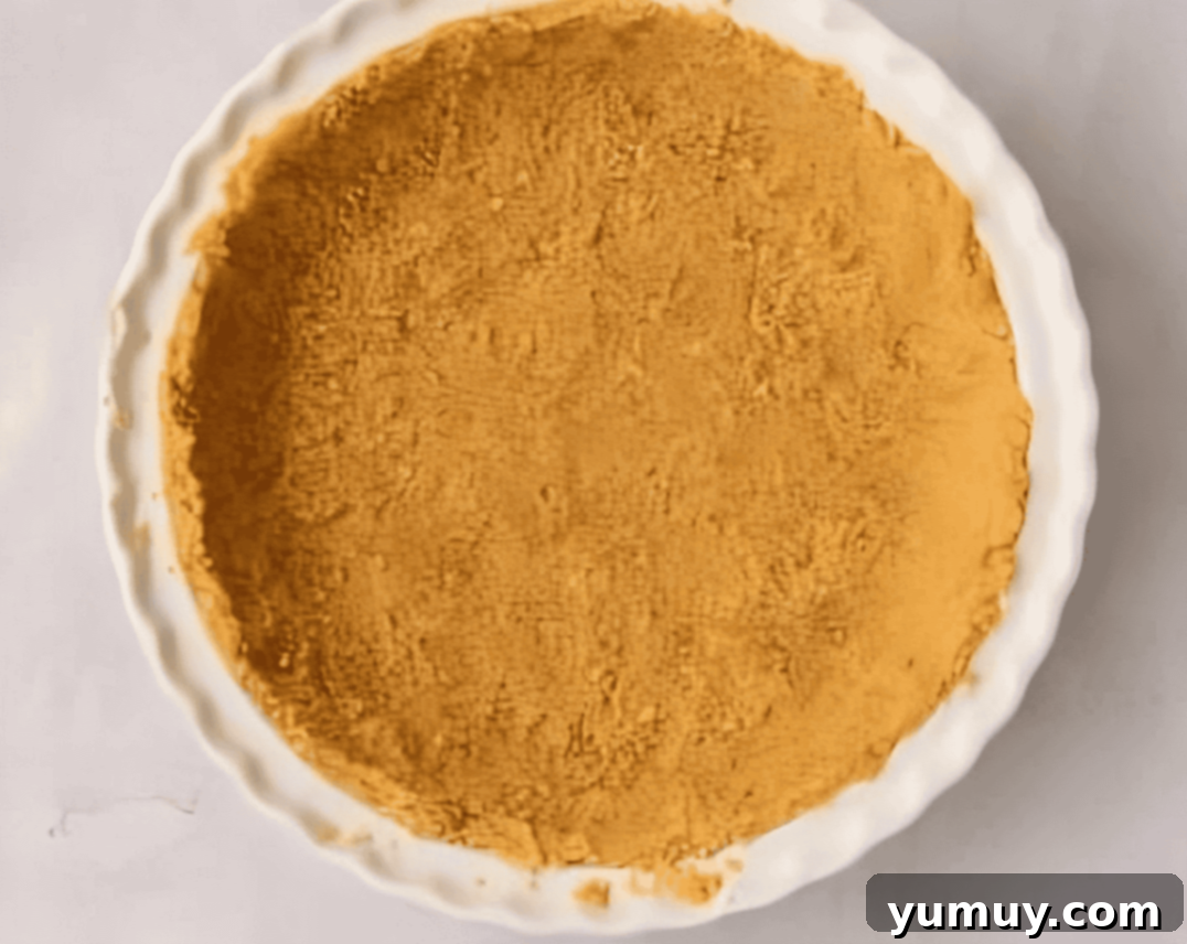 Sunshine Slice 9 graham cracker crust pressed into a ceramic pie dish, ready for baking.