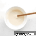 glaze in a white bowl with a rubber spatula.