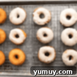 glazed donuts on a wire rack set in a baking sheet.