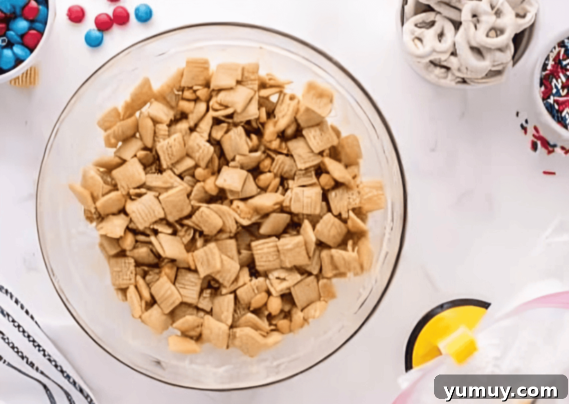 chex and peanuts coated in peanut butter white chocolate in a glass bowl.