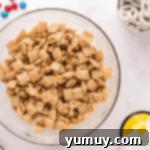 chex and peanuts coated in peanut butter white chocolate in a glass bowl.