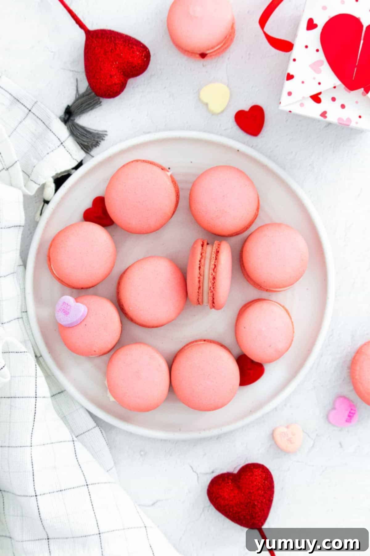A close-up of beautifully baked pink Valentine's Day macarons, showcasing their smooth tops and delicate 'feet', ready to be filled and enjoyed.
