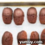chocolate dipped chocolate madeleine cookies on baking sheet