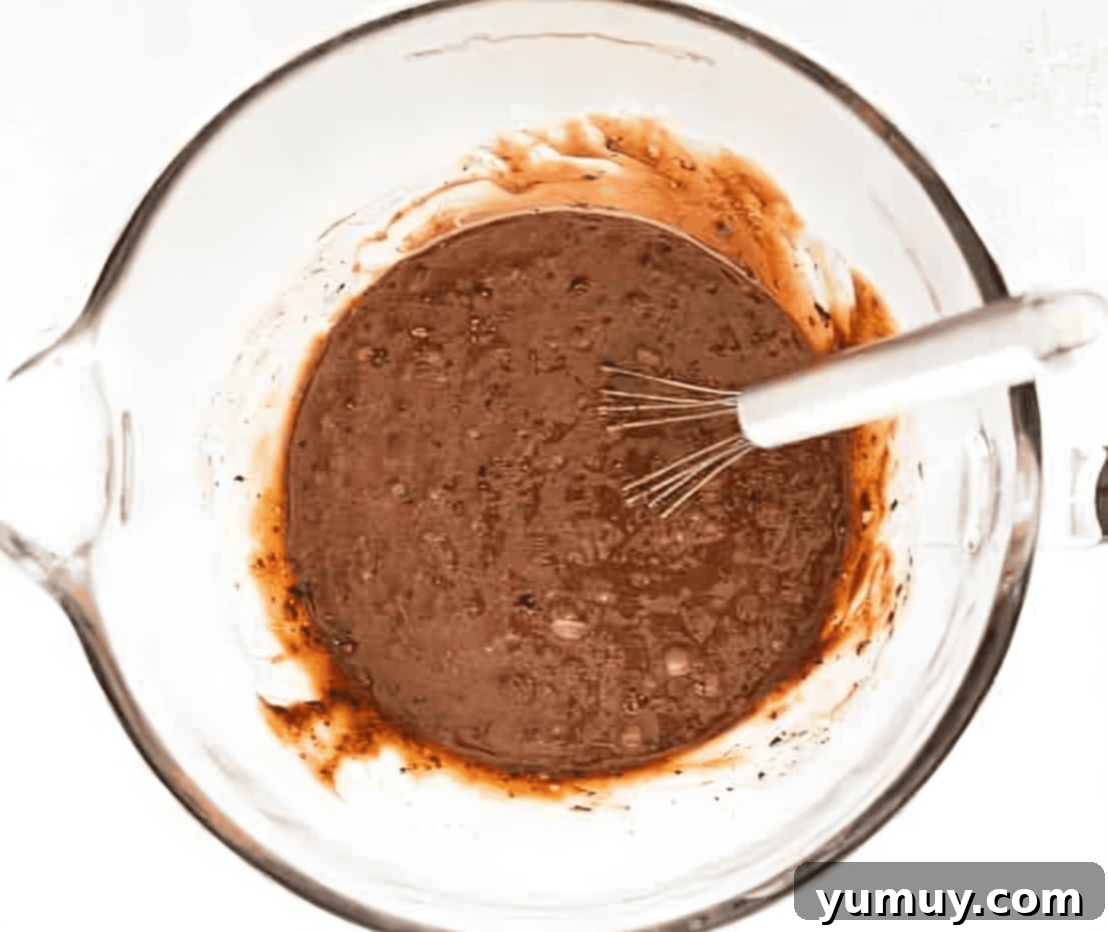 chocolate cake batter in a glass bowl with a whisk.