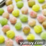 Jello-coated candy grapes on a baking tray lined with parchment paper.