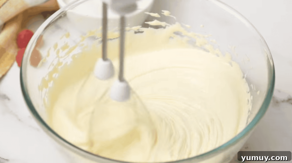 Pan di Spagna 14 Egg yolks and sugar being beaten together in a glass bowl to a thick, pale yellow state using a hand mixer.