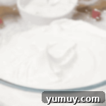 Pan di Spagna 6 Perfectly whipped egg whites in a glass bowl, forming stiff peaks.