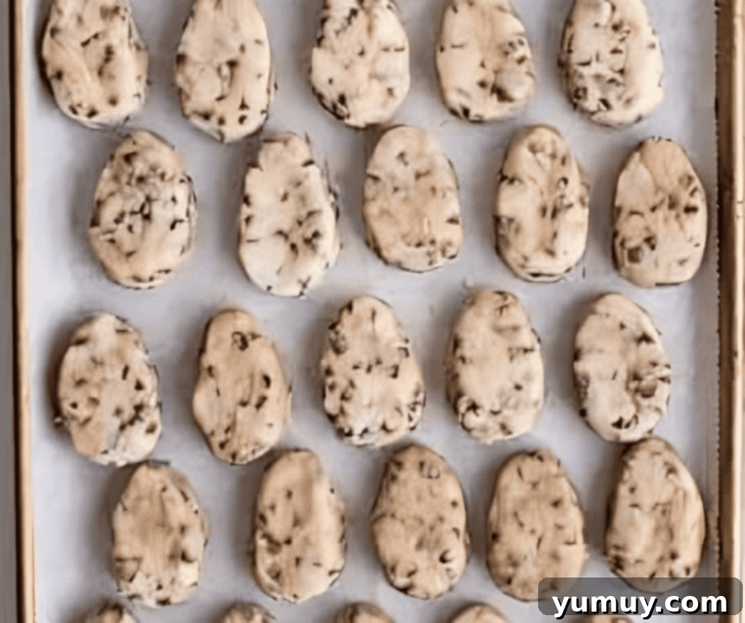 Neatly shaped egg-shaped cookie dough truffles on a parchment-lined baking sheet.