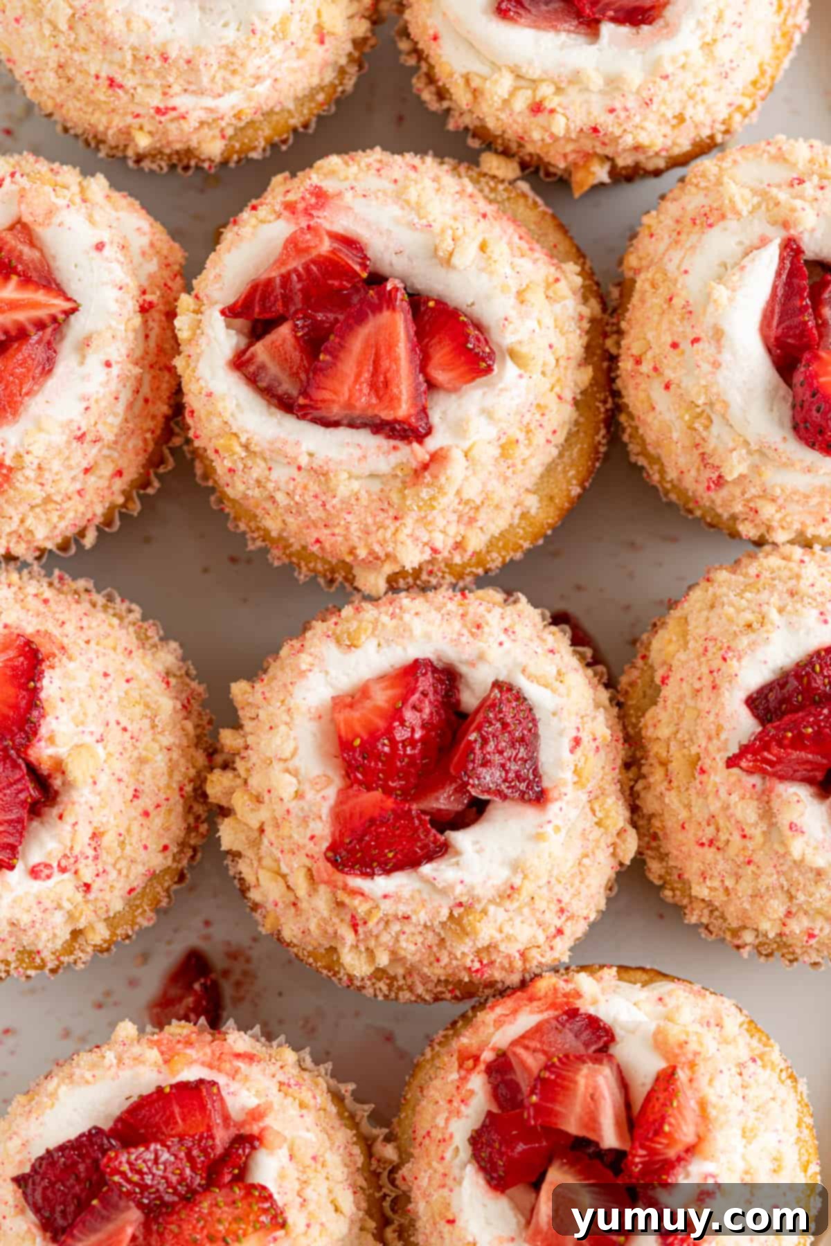 An overhead view of delightful strawberry shortcake cupcakes, topped with fresh berries and cream.