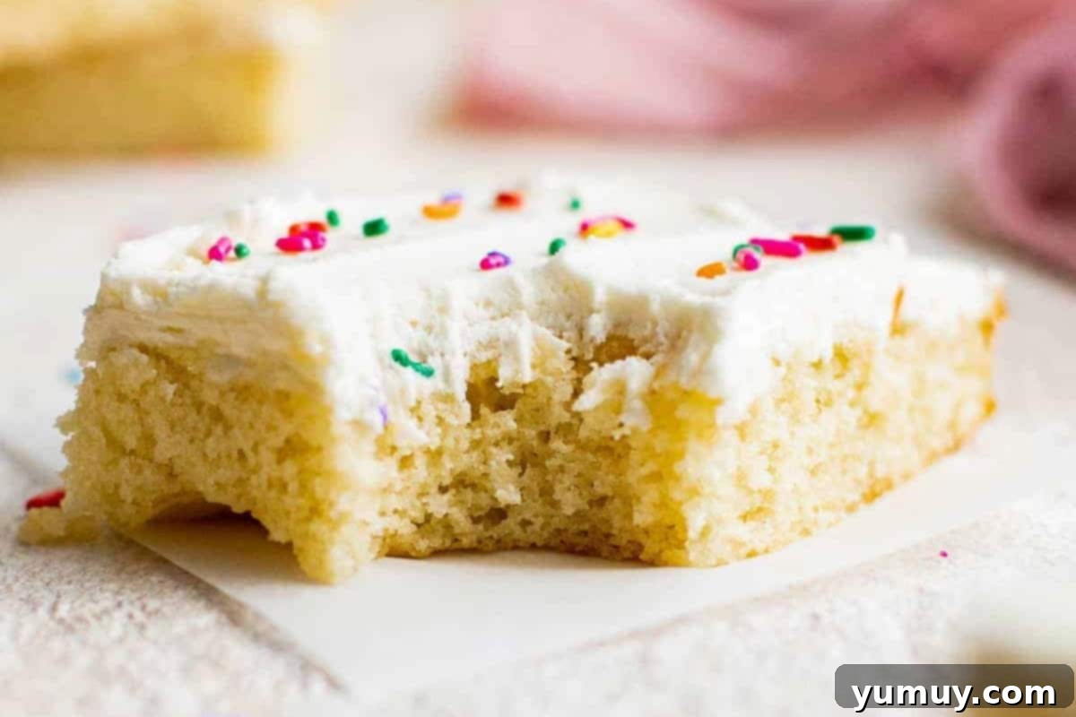 Luscious Vanilla Sheet Cake 3 closeup of a slice of frosted vanilla sheet cake missing a bite.