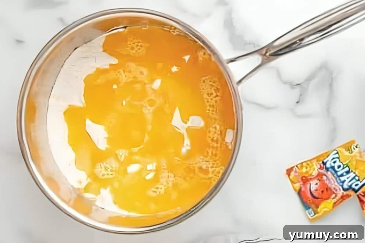 Fun Fragrant Kool Aid Playdough 12 Water and oil being added to a pan containing the Kool-Aid powder and dry playdough ingredients, mid-stir.