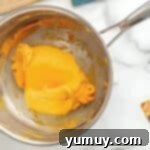 Fun Fragrant Kool Aid Playdough 7 Orange playdough mixture coming together and thickening in a saucepan over heat.