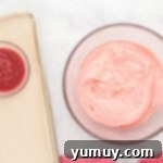 a bowl of strawberry icing next to a bowl of icing.