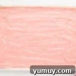 a pink frosted cake in a baking pan.