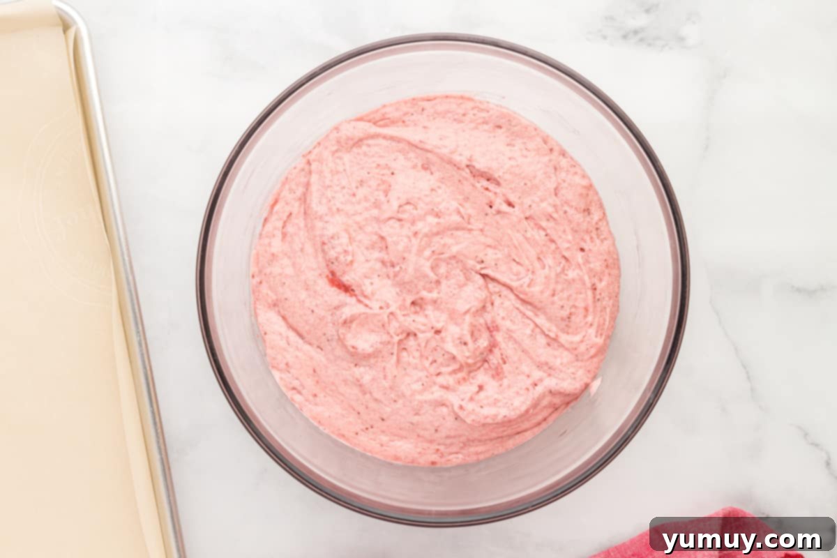 strawberry cake batter in a bowl on a marble countertop.